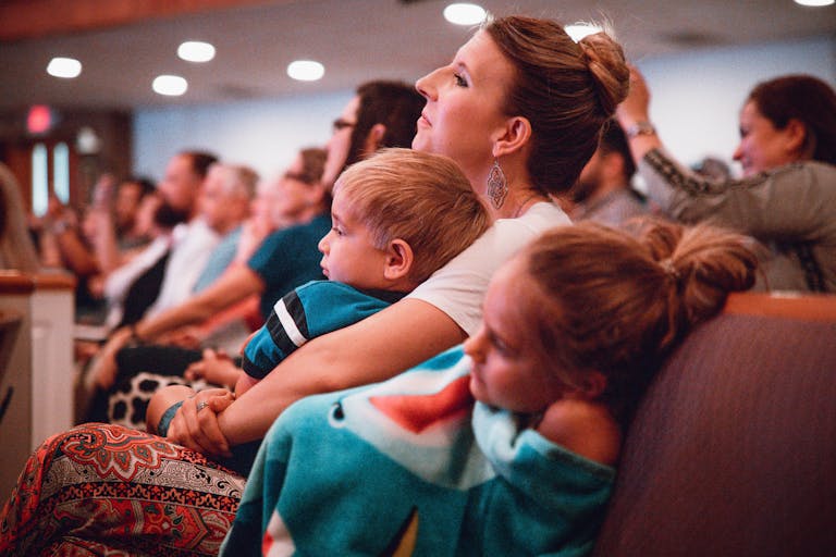 A mother and her children attentively listening indoors, with a warm family bond visible.