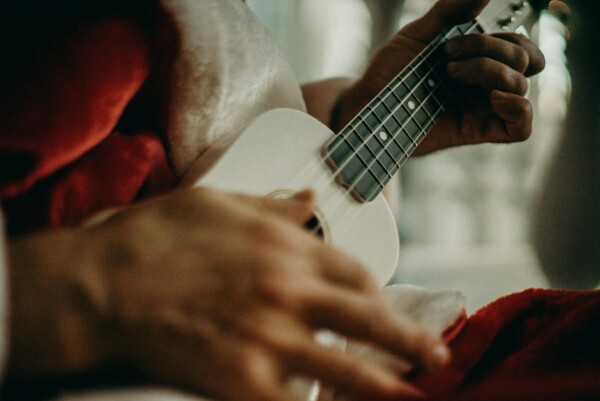 Close-up of a person playing a ukulele in a cozy indoor setting with soft lighting.