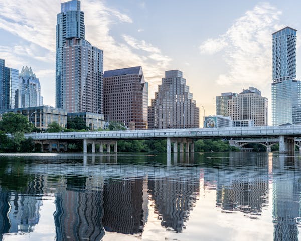 Beautiful view of Austin's skyline with reflections in Lady Bird Lake during daytime.